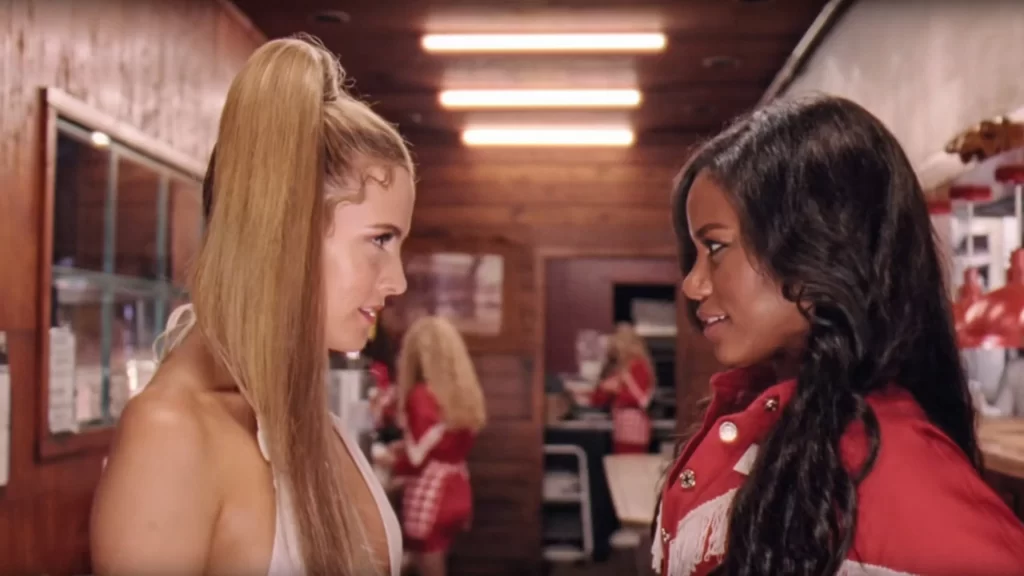 Taylour Paige, a black woman with long brown hair, playing the character Zola stands opposite Riley Keough, a white woman with long blonde hair who plays Stefani in the movie Zola