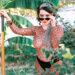 Delphine, a brunette white woman, is wearing a leopard leotard and tights with black lacy underwear. She has a leopard scarf around her hair and is holding a shovel under a banana tree. She has sunglasses and her blue eyes peer out from behind them like she is inviting you to share a drink with her. She is an escort in the SF Bay Area.