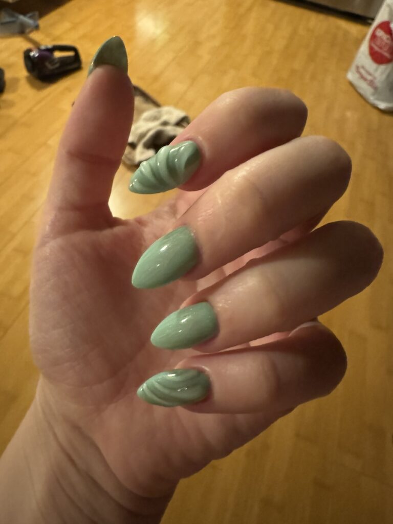 Close up of Delphine's nails. They are blue with clear texture on them that looks like a seashell.