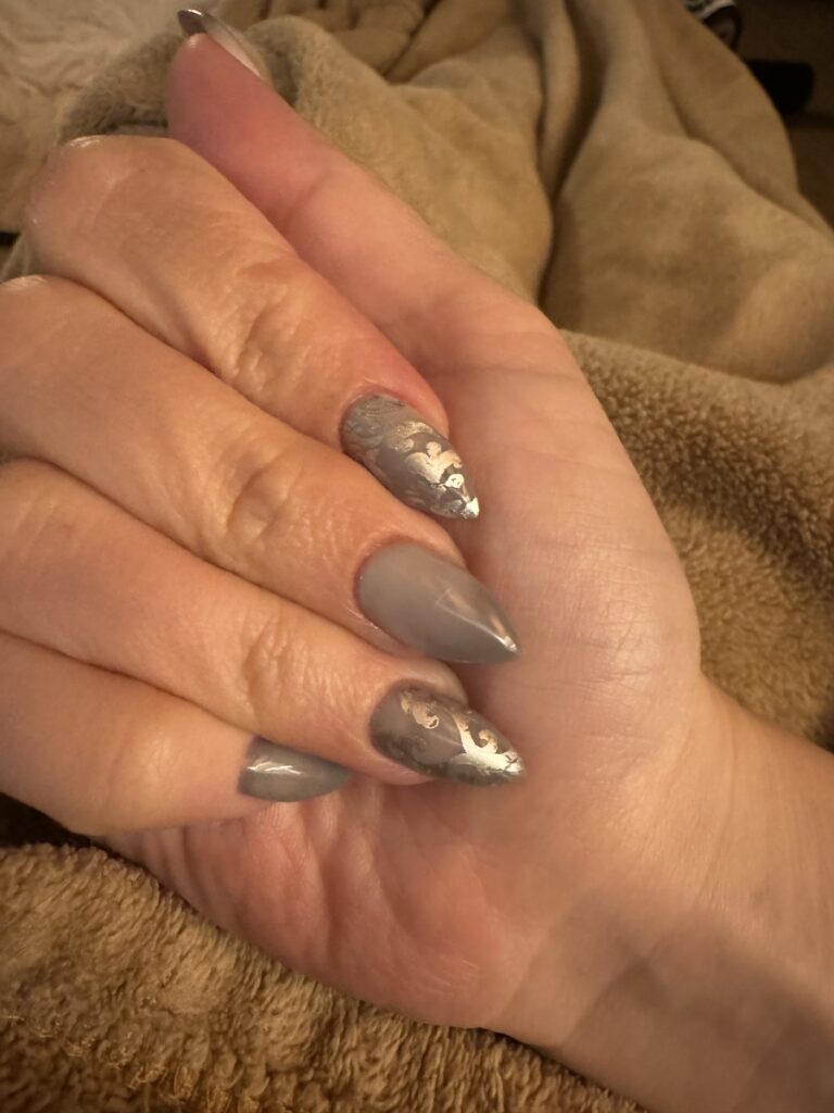 Close up of delphine's nails. They are grey with silver brocade design.