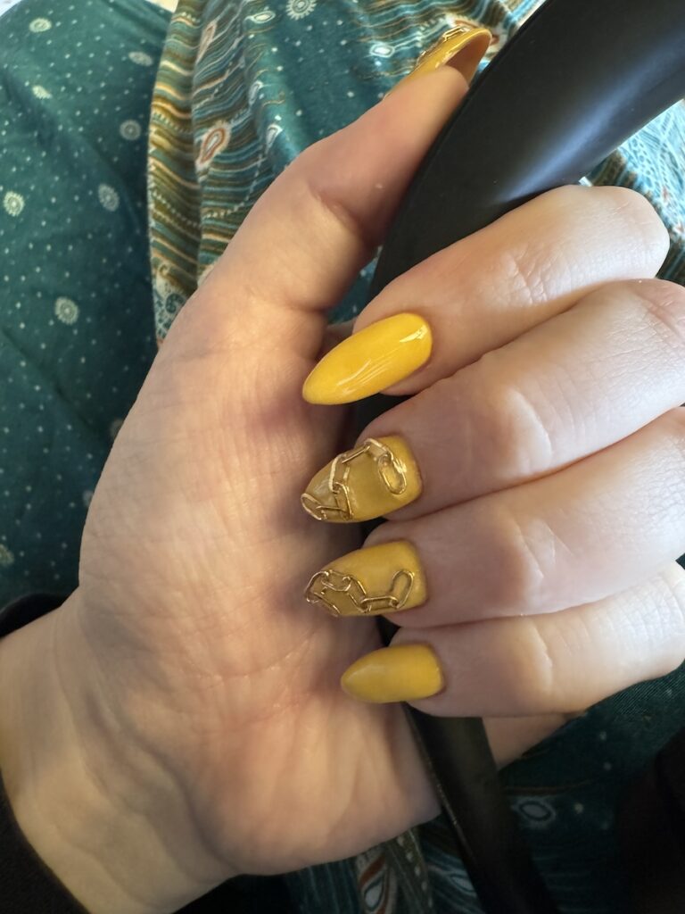 Delphine's nails are yellow with a gold chain glued onto some of them.